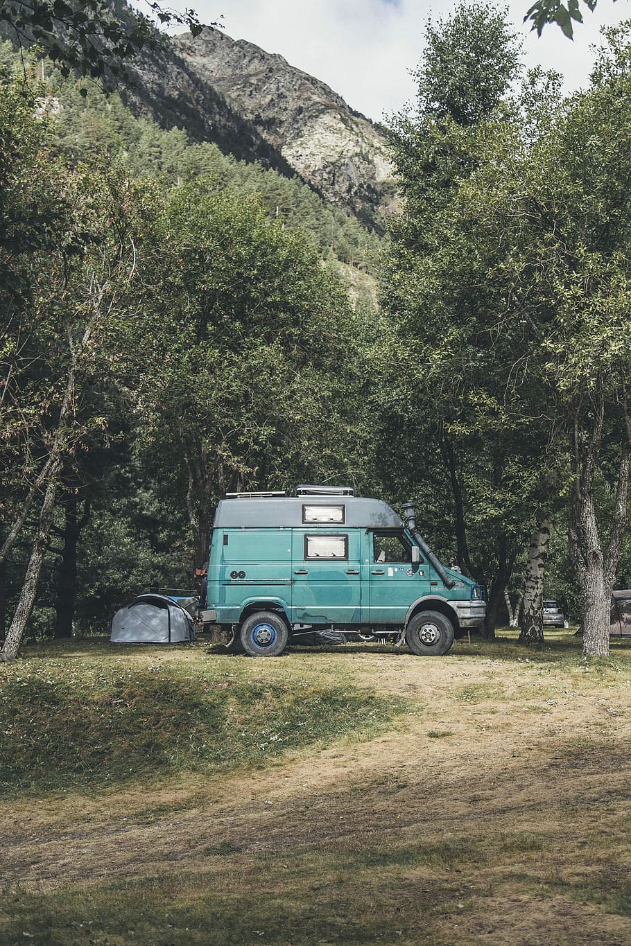 landscape photography of parked teal and black conversion van near trees, parked green minivan surrounded with trees at daytime HD wallpaper