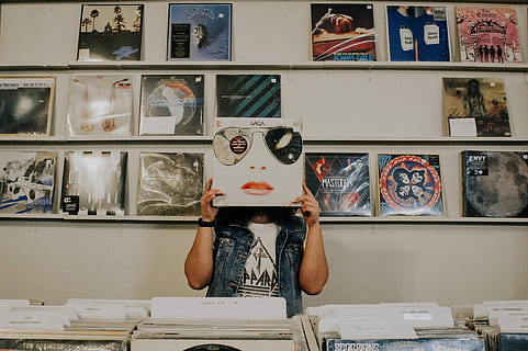 person covering face with vinyl sleeve, person holding vinyl sleeve standing near display HD wallpaper