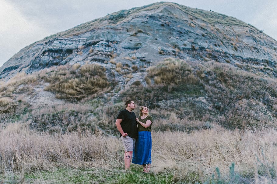 man and woman standing near mountain, man and woman taking photo near hill HD wallpaper
