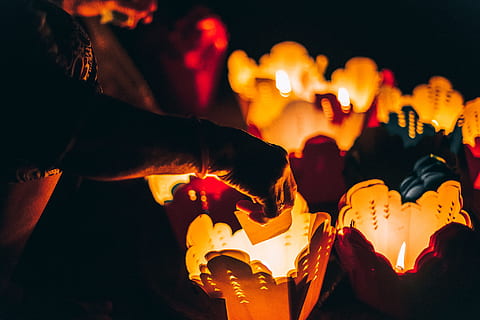 person burning paper on lighted candles, low light photography of person holding white paper near white basket with candle HD wallpaper