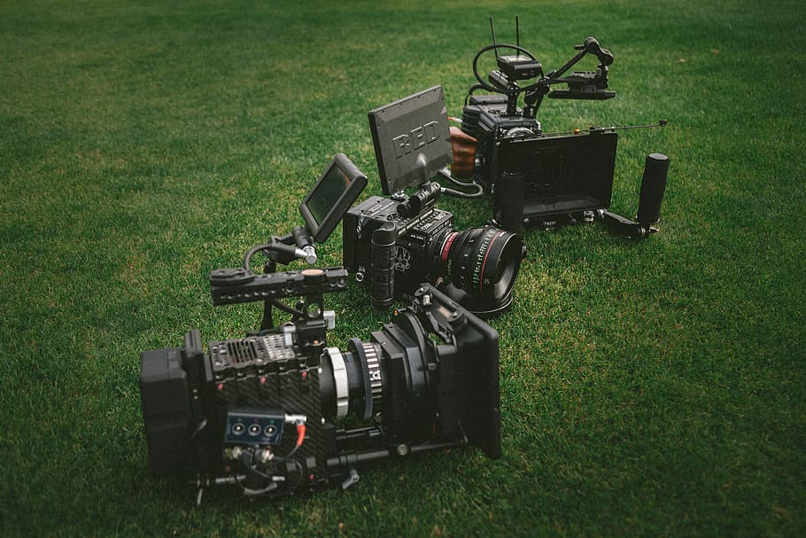 three black video cameras on green grass field, three black professional video cameras on green grass field HD wallpaper
