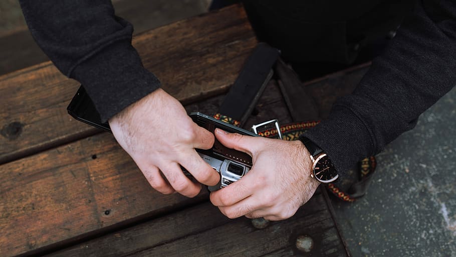 person holding film camera, man holding camera, table, wooden HD wallpaper