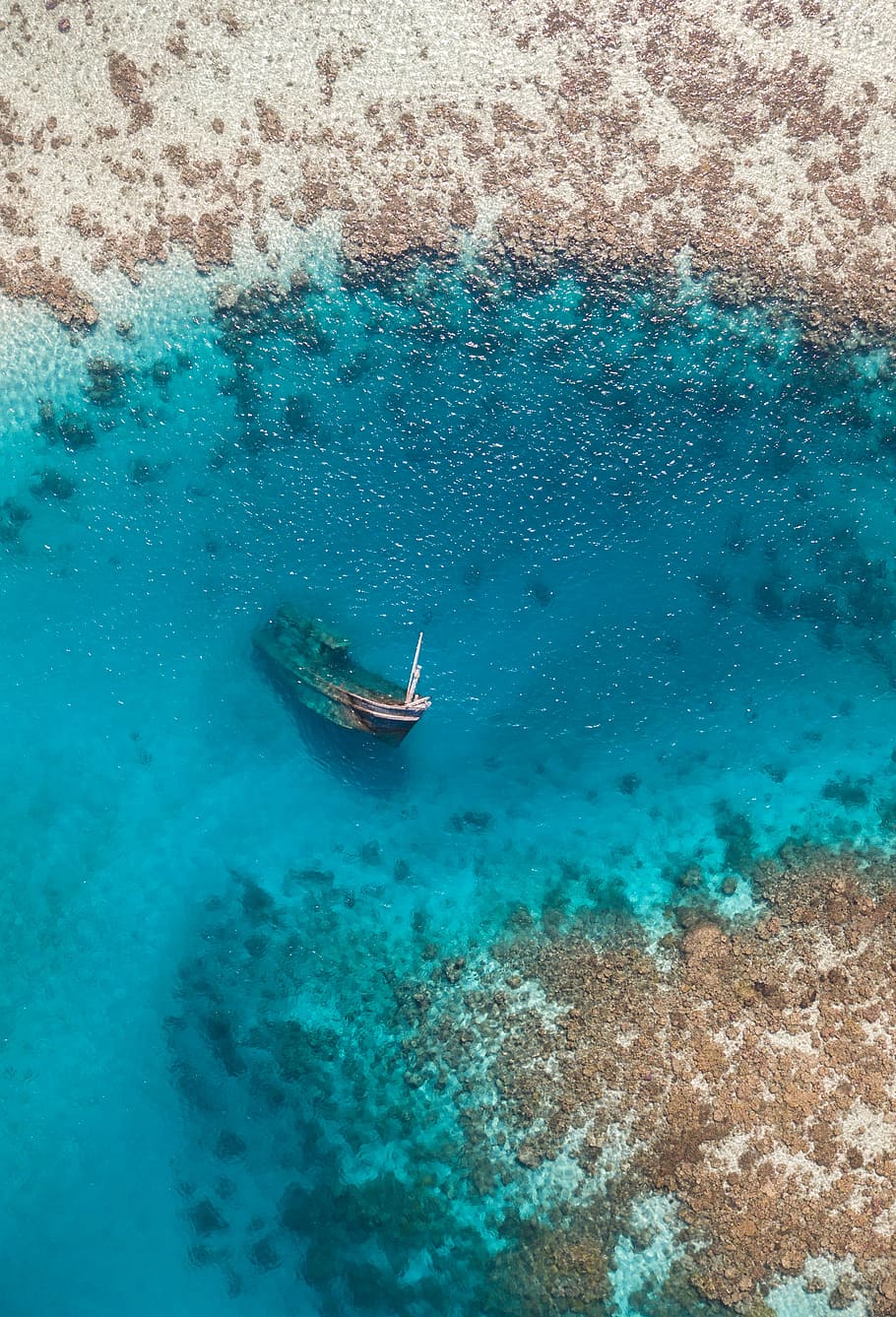 aerial photo of grey boat sink at the blue sea water, sunk boat on body of water