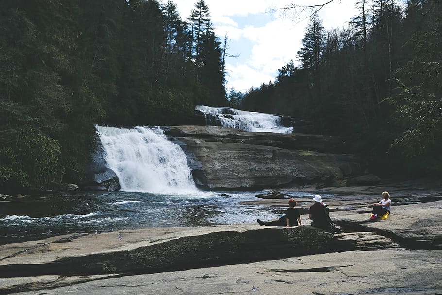 three people sitting on gray surface in front of waterfall, group of people looking at waterfalls HD wallpaper