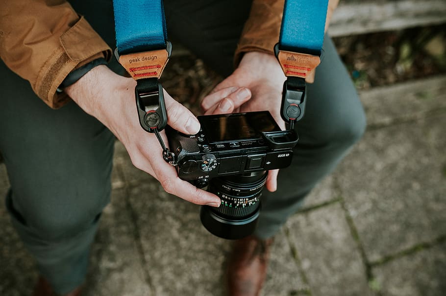 person holding black DSLR camera, person holds camera with strap white sitting HD wallpaper