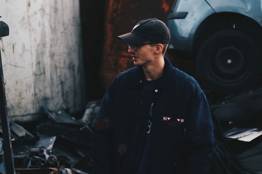 man wearing black cap facing side, man standing beside vehicle HD wallpaper