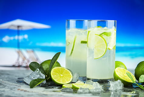 two clear drinking glass with liquid and lime fruits, beach HD wallpaper