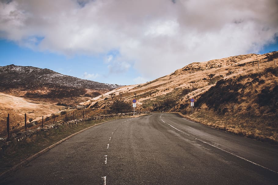 Concrete Road Near Mountains, asphalt, clouds, grass, sky, traffic sign HD wallpaper