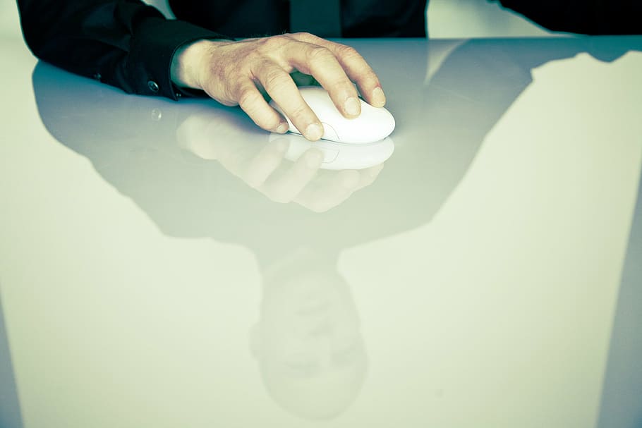 person holding white cordless computer mouse on white table HD wallpaper