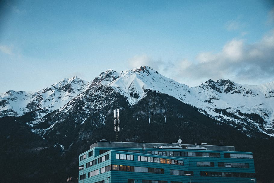 landscape photography of snow-top mountain, grey building near the mountain HD wallpaper
