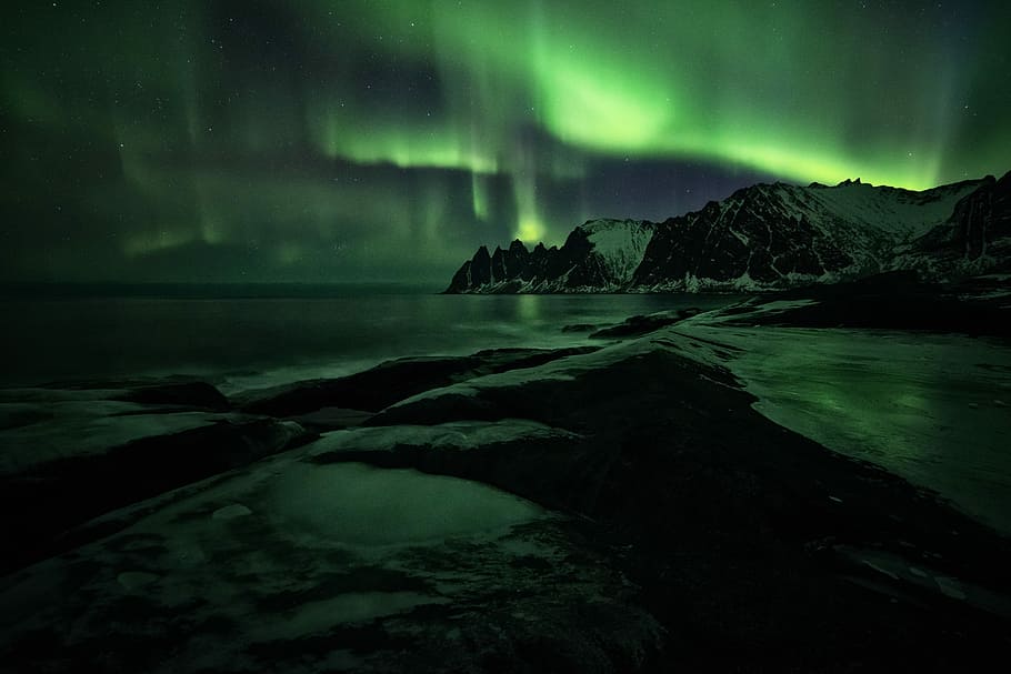 Northern Lights over mountain, body of water near brown and white mountain under Aurora lights