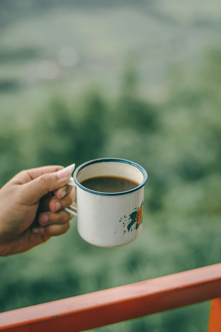 person holding white and orange floral mug, person holding white and blue cup of coffee HD wallpaper