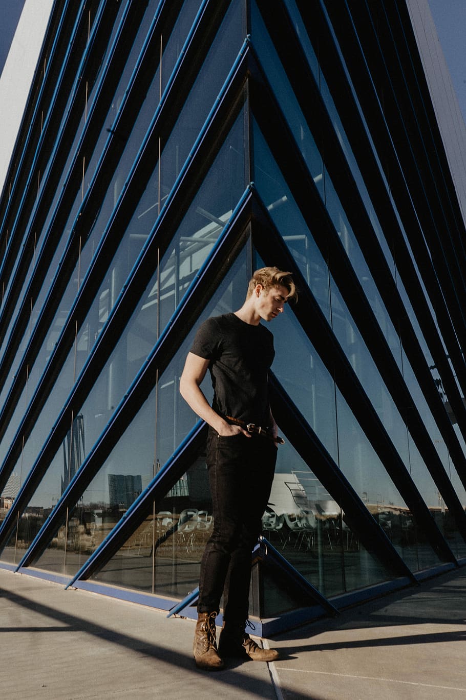 man standing beside building, man standing on concrete floor near building HD wallpaper