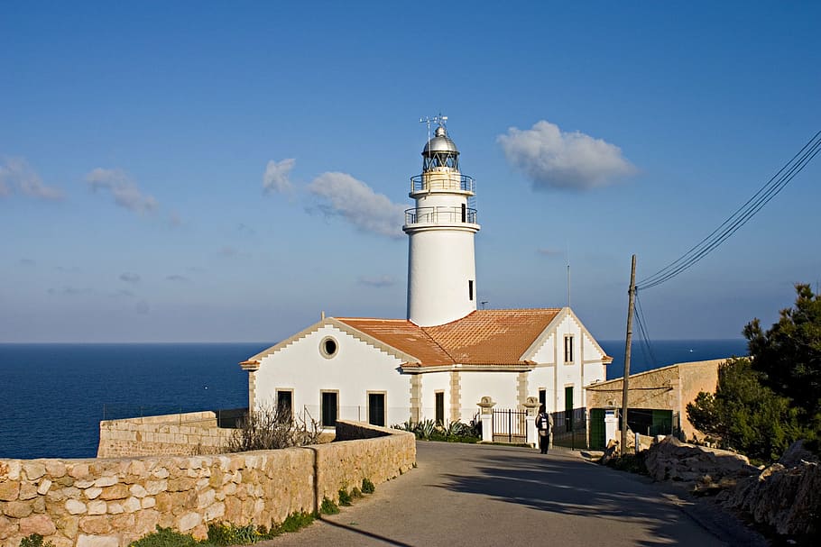 white and brown concrete house and white lighthouse beside water during daytime HD wallpaper