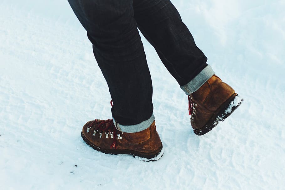 person standing on snowfield during daytime, person wearing black jeans standing on snow covered groiund HD wallpaper