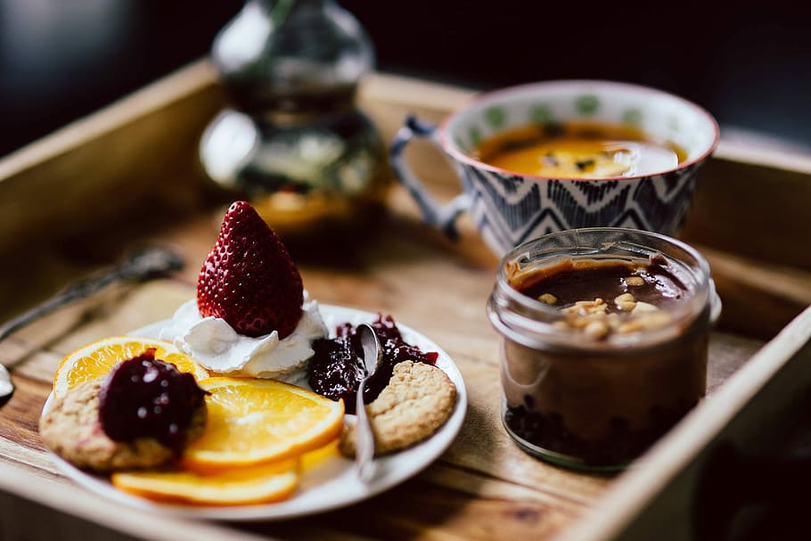 Room service tray at hotel for breakfast: cookies, jam, chocolate mousse, orange fruit, tea HD wallpaper