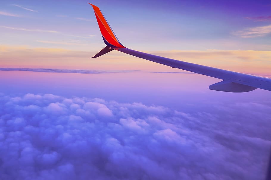 person in a plane flying at high altitude taking photo of left airplane wing during daytime, white and red airplane above clouds HD wallpaper