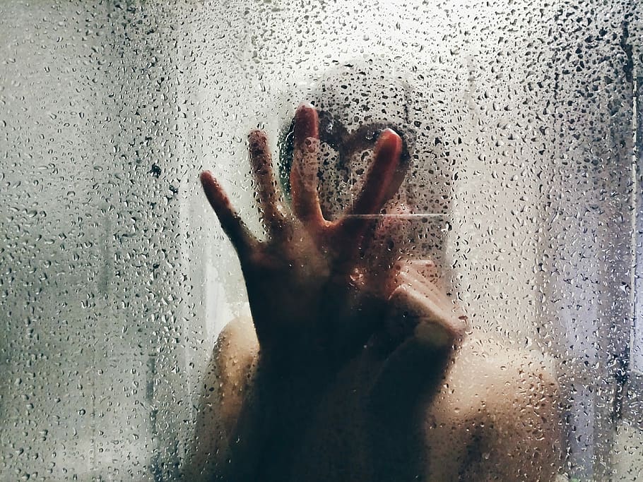 person touching clear shower glass, person holding glass window