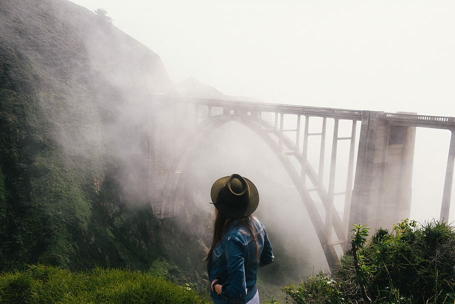 woman in cowboy hat and blue denim jacket standing on cliff with a view of concrete train bridge covered with fogs, HD wallpaper