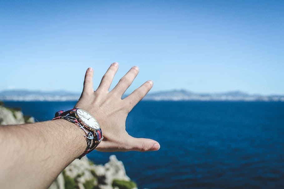 person trying to reach mountain, person wearing round gold-colored analog watch HD wallpaper