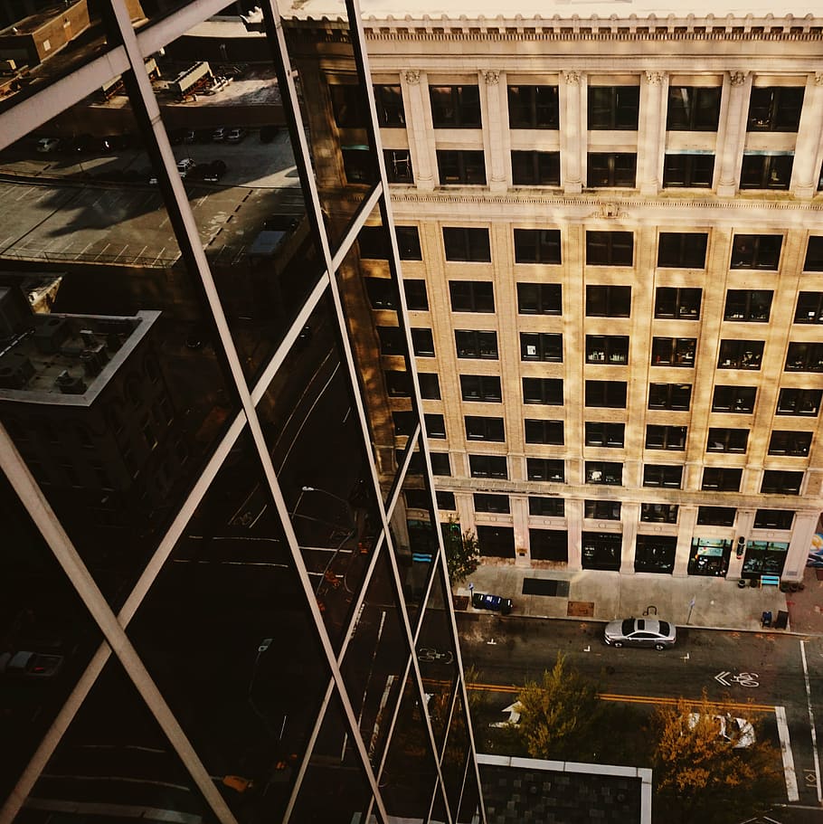 high angled photography of building near street with vehicles on front of other building HD wallpaper