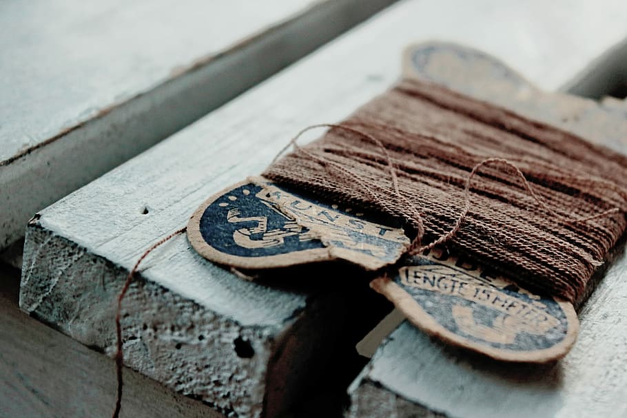 brown sewing thread on white surface, tilt shift lens photography of brown thread on gray wooden planks HD wallpaper
