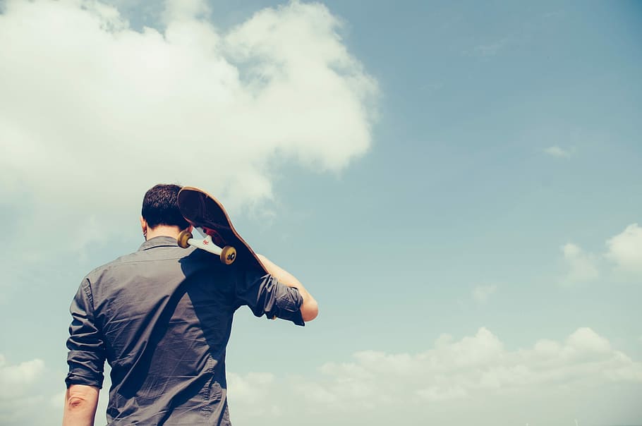 man holding black skateboard during daytime, outdoors, nature HD wallpaper