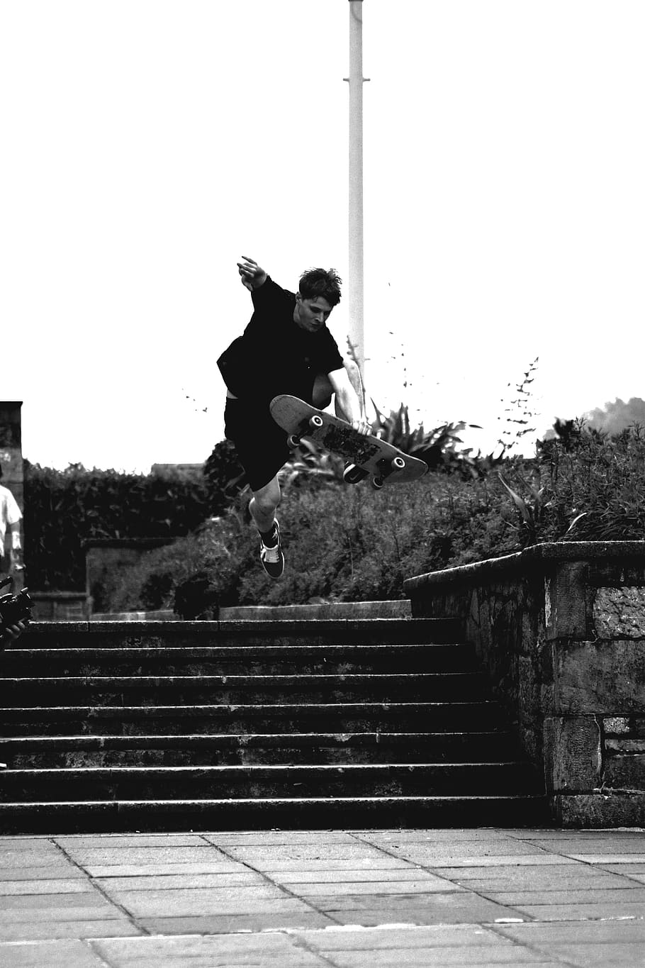 Grayscale Photo of Man Doing Trick on Skateboard on Park, action