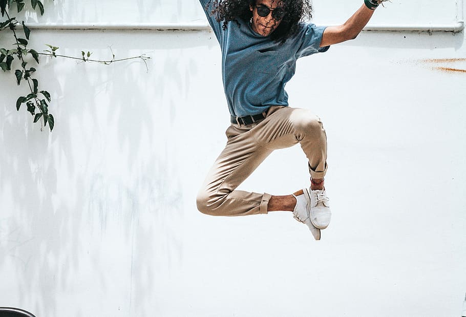 man jump on front of wall, man wearing blue shirt and brown pants jumping HD wallpaper