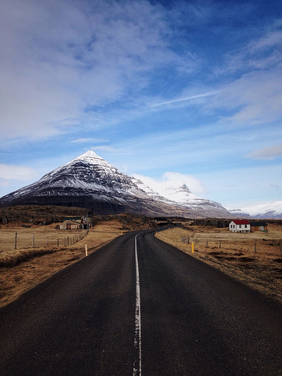 gray asphalt road in between brown plants, clear road in between brown field near mountain under white clouds and blue sky HD wallpaper