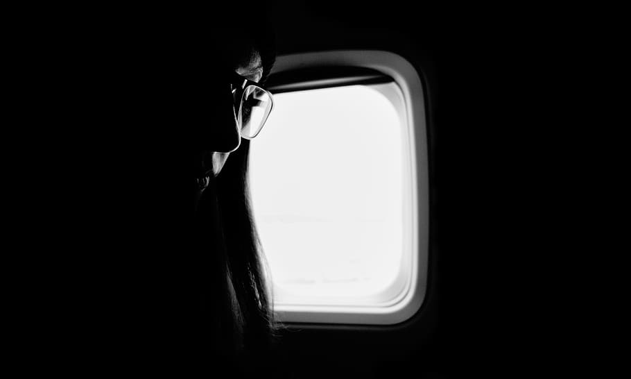 grayscale photography of woman near window, black and white, plane window