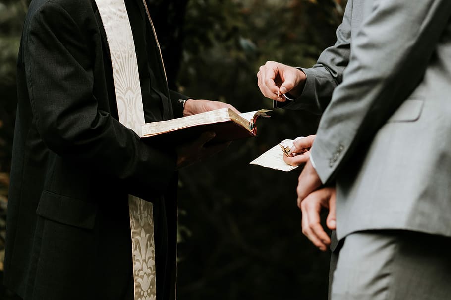 priest holding bible, person holding bible standing in front of two men in gray suits HD wallpaper
