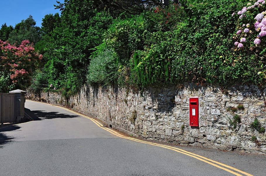 red mail post mounted on wall during daytime, st mawes, roseland peninsula