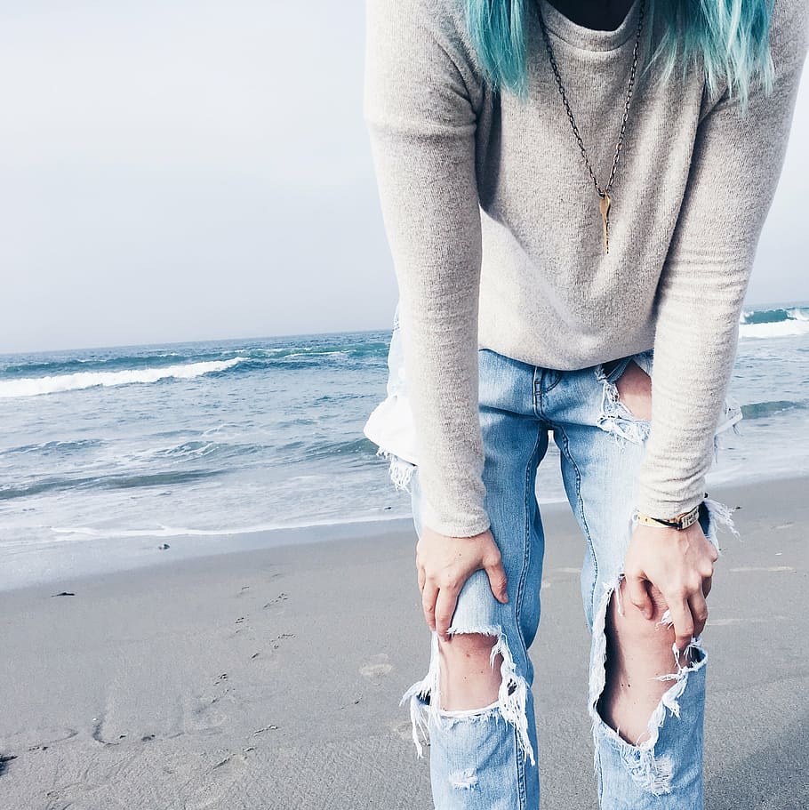 person wearing gray crew-neck long-sleeved shirt and distressed blue denim jeans standing on shore during daytime HD wallpaper