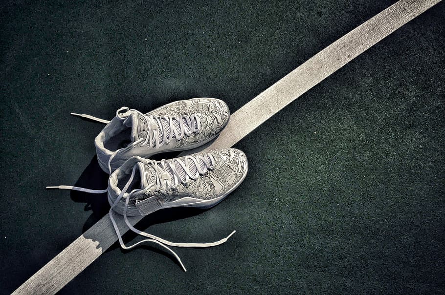 unlaced gray-and-white basketball shoes on black and white surface