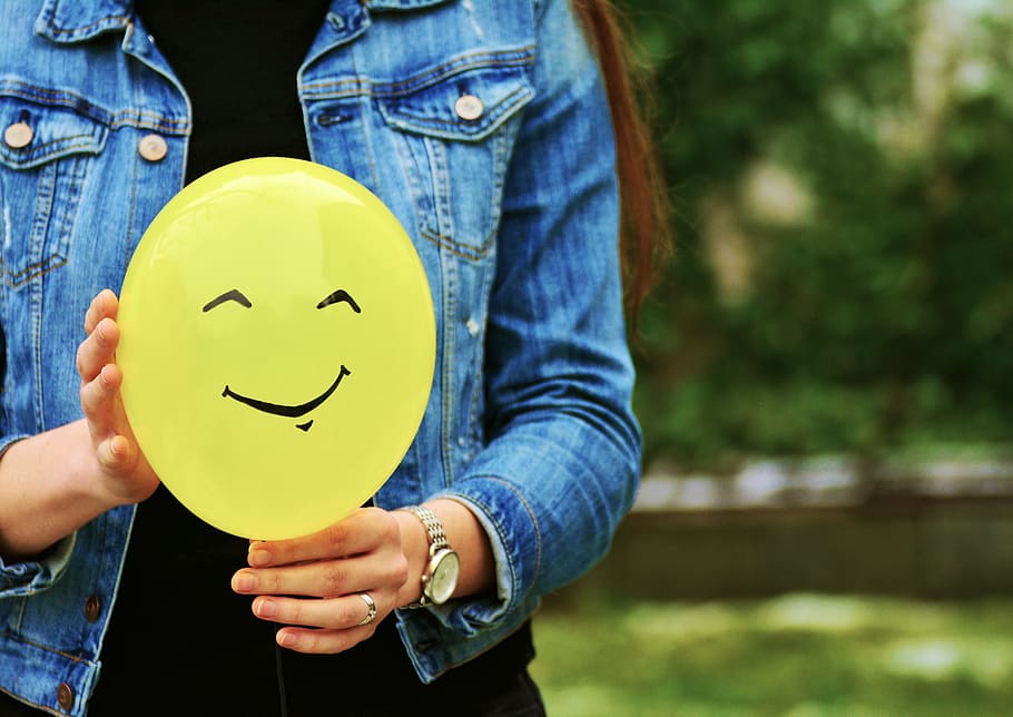 woman in blue denim jacket holding yellow plastic balloon, hands HD wallpaper