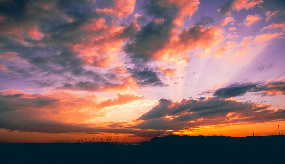 silhouette of hills under orange and gray sky at golden hour, sunrays through clouds at sunset HD wallpaper