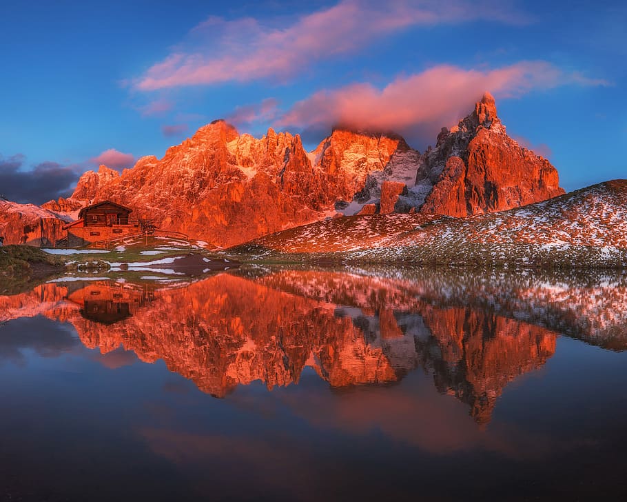 low angle photo of stone hill near bodies of water under blue sky at daytime, body of water near rocky mountain HD wallpaper