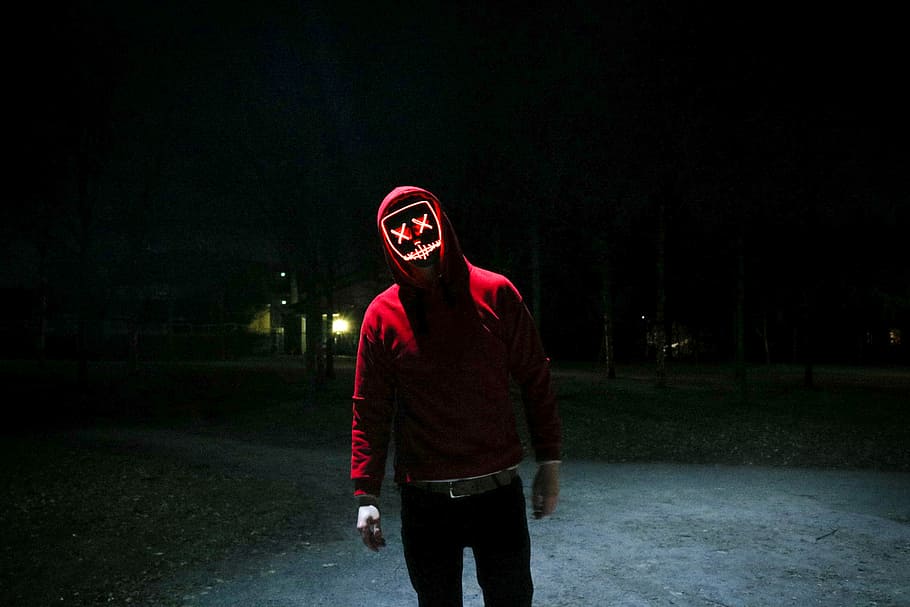 person in red pullover hooded jacket standing in street during nighttime, Marshmello standing outside during night