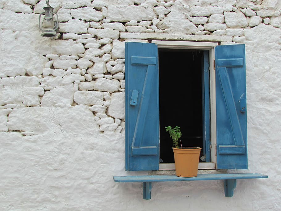 brown flower pot on wall mount rack near window on wall, karpathos