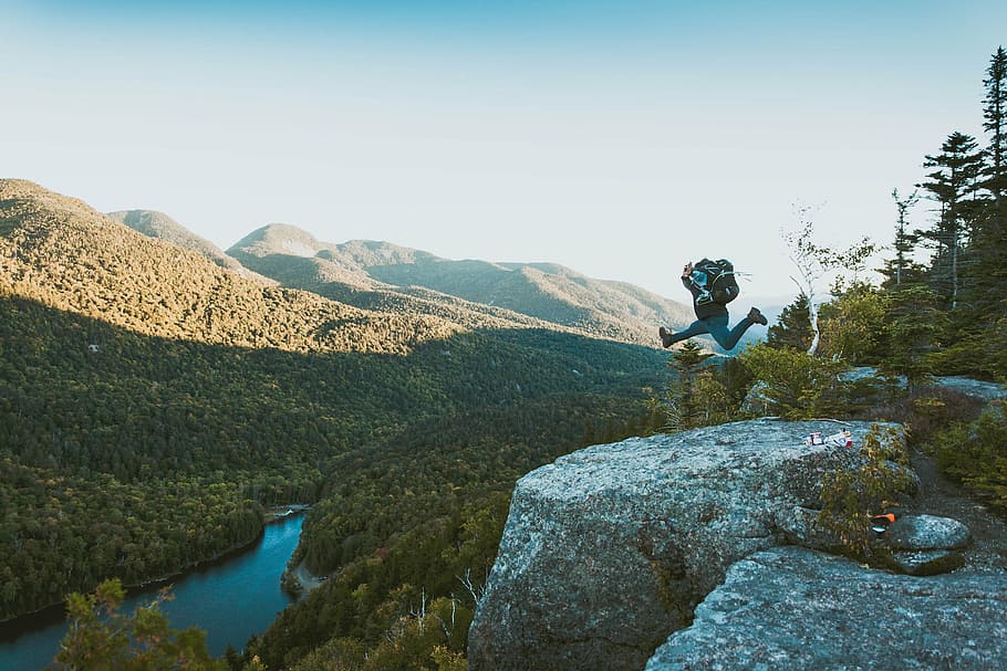 man jumping on gray rocky mountain during daytime, nature, landscape HD wallpaper