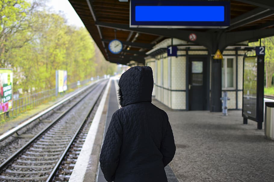 person in hoodie standing near train rail during daytime, person standing on subway HD wallpaper