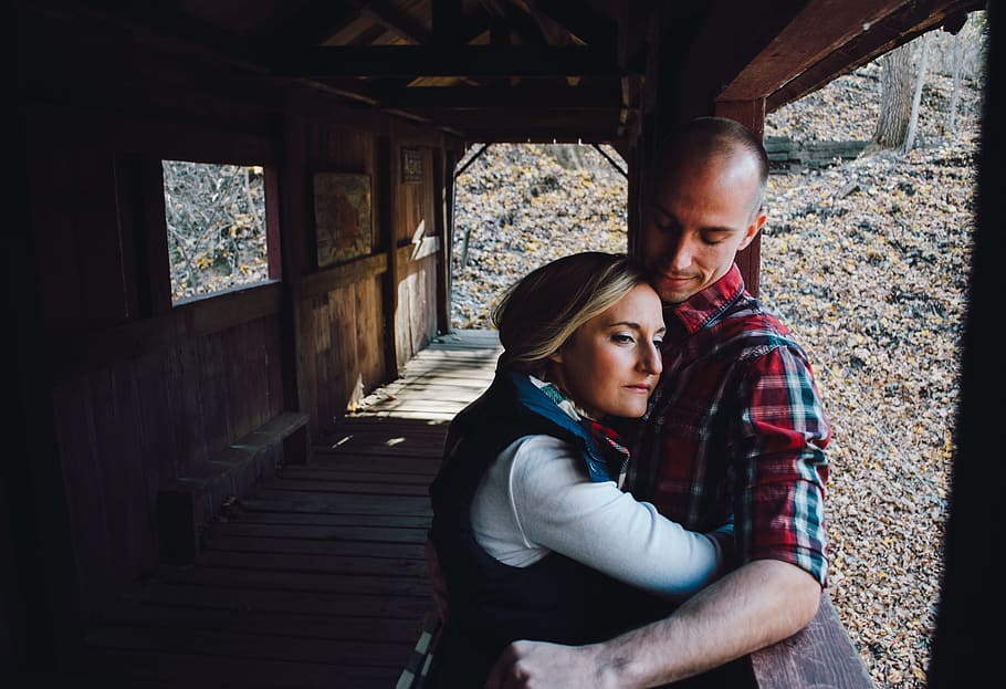 woman hugging man inside bridge during daytime, woman hugging man while leaning on brown wall HD wallpaper