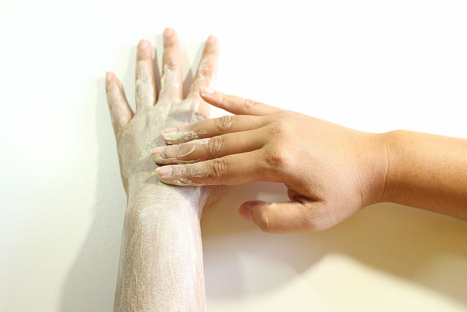 applying white cream on left hand