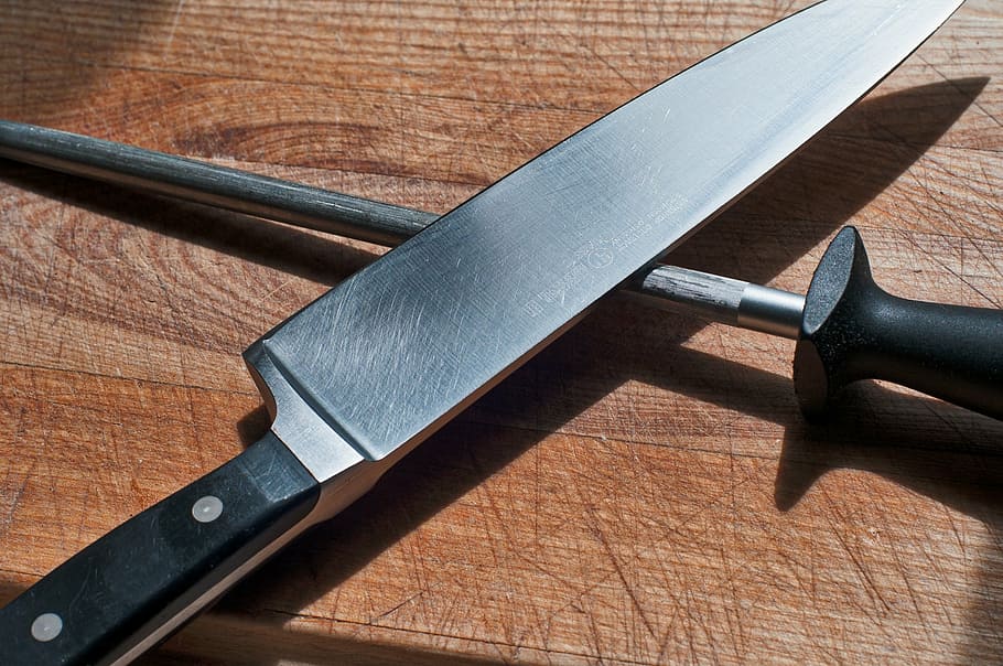 gray knife with black handle, cutting board, sharpening steel