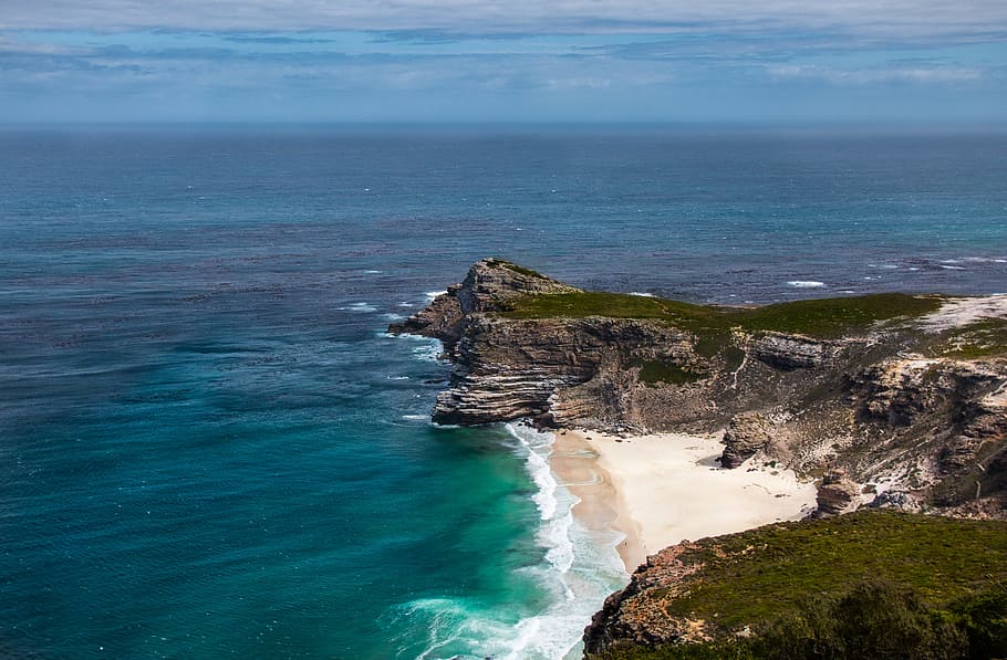 waves crashing on rocks, aerial photo of body of water and cliff under blue sky during daytime HD wallpaper