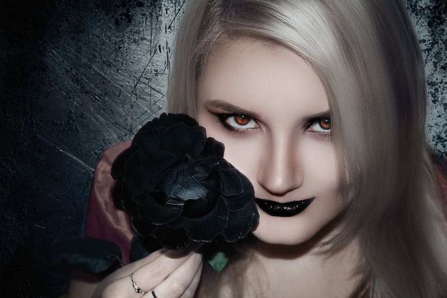 gray haired woman holding black rose flower with black lipstick