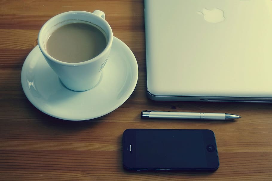white ceramic cup filled with coffee on white saucer near silver MacBook HD wallpaper