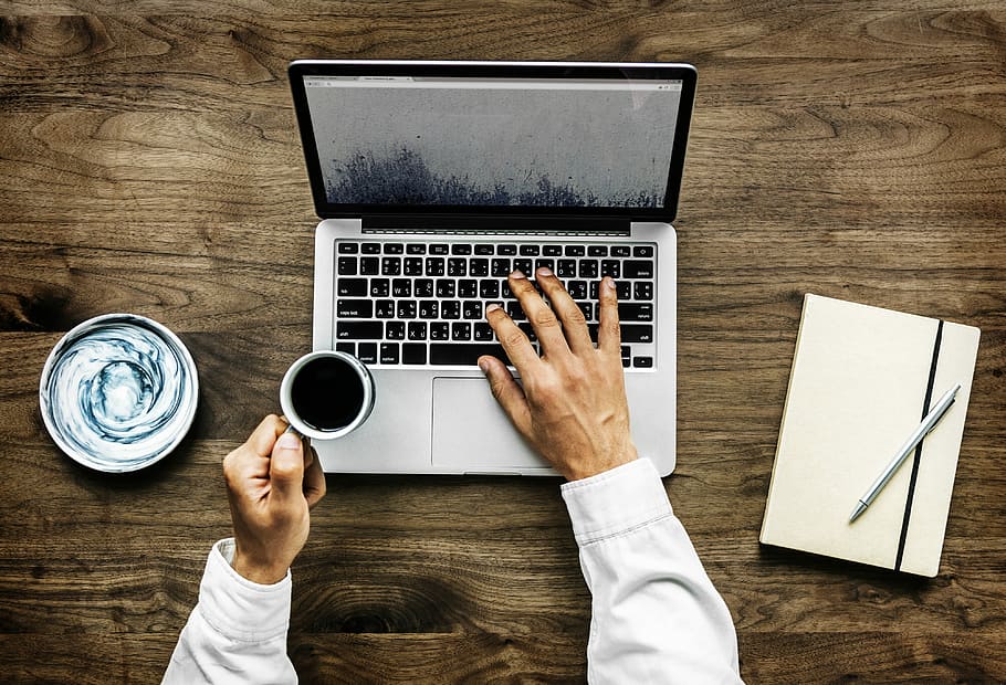 person holding a cup of coffee while using a laptop, aerial HD wallpaper