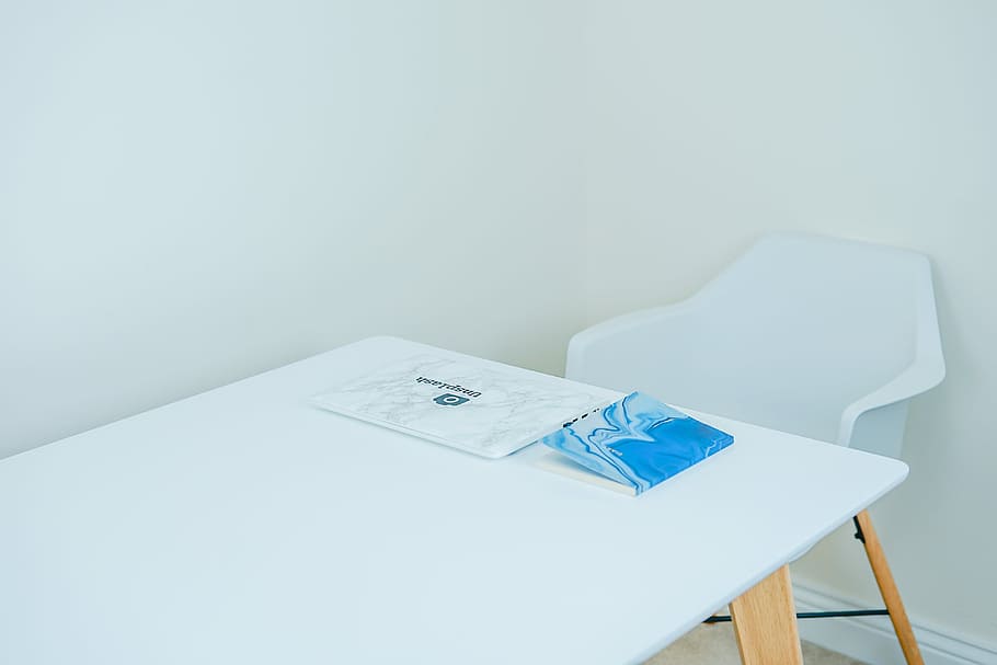 blue covered book on white table with armchair in front, white and brown wooden table beside chair HD wallpaper